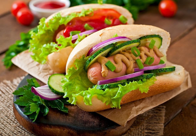 Hotdog with ketchup, mustard, lettuce and vegetables on wooden table