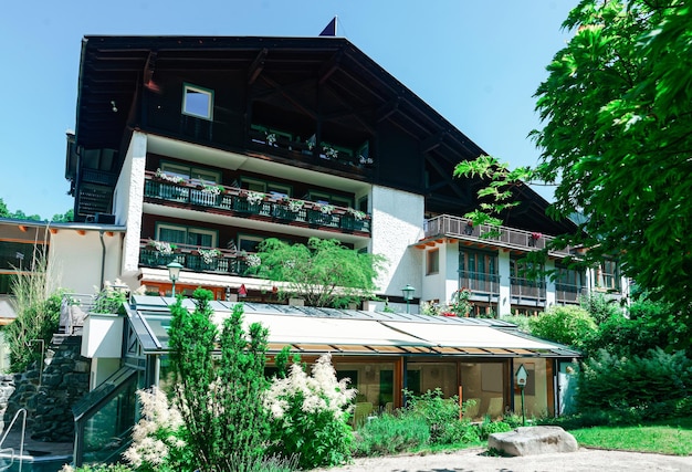 Hotel family resort and landscape with nature in summer in Austria. Modern wooden house design among mountains. Exterior facade of building complex. Villa front view. Relax on holiday.