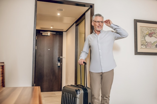 In a hotel. Gray-haired confident man in a hotel room