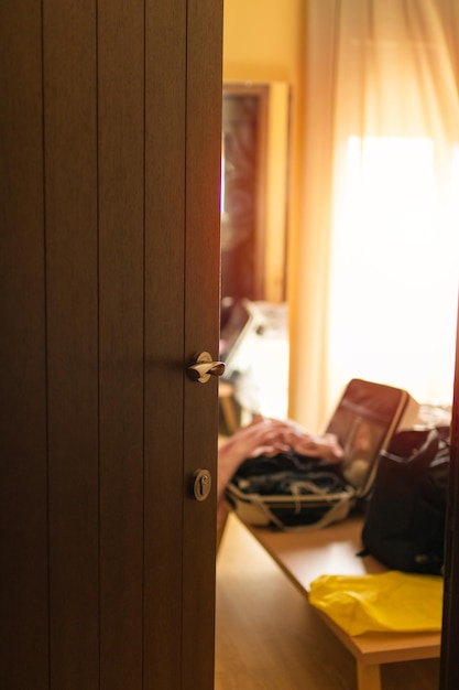 Hotel room door ajar sunny window in the background and suitcases