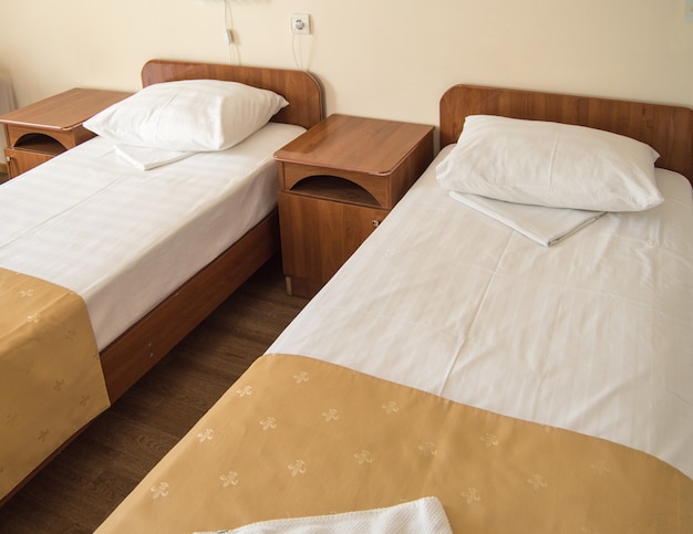 Hotel room with two empty SINGLE beds and bedside tables, the concept of the hotel business.