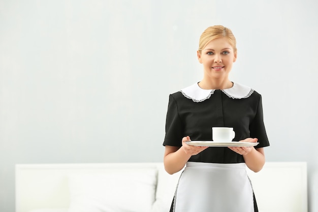 Hotel service concept Chambermaid holding tray with cup of coffee