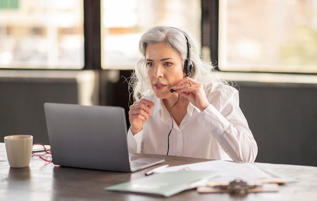 Hotline operator woman wearing headset making video call in office