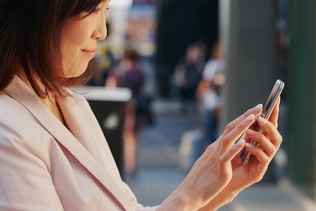 The hottest wifi spot on the block. Shot of a young businesswoman using a smartphone against an urban background.