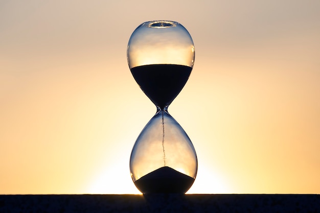 Hourglass counts the length of time against the background of the evening sun