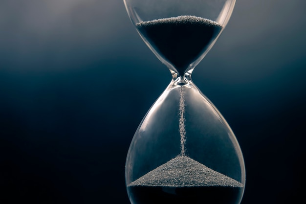 Hourglass on a dark background. Time is money. Business solutions in time.