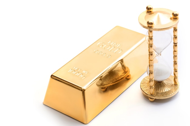 Hourglass and fine gold bullion. Concept of investment in the precious materials.