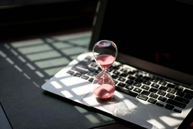 Hourglass sand timer on top of laptop