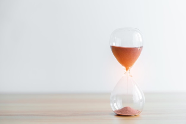 Hourglass on table Sand flowing through the bulb of Sandglass measuring the passing time countdown patience deadline Life time and Retirement concept