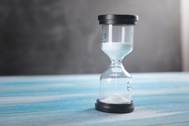 Hourglass on wooden surface .