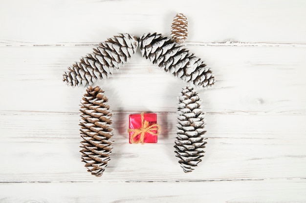 A house made of cones and a red gift box on a white wooden