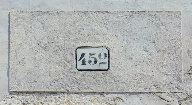 House number 452 sign to old white wall