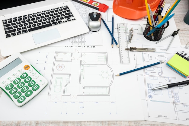 House project plan with work tools and helmet on desk