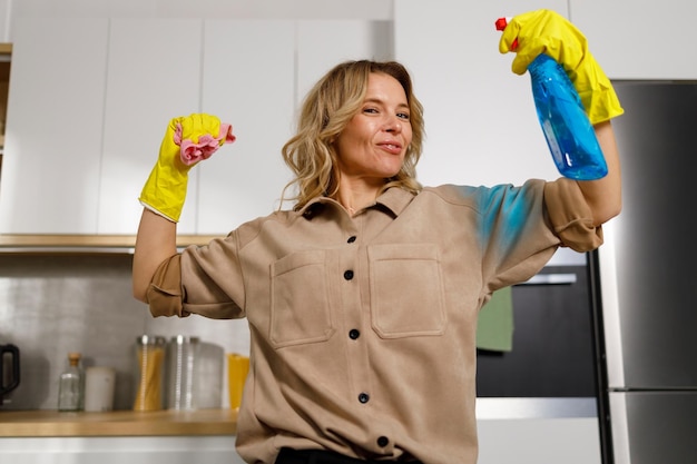 Housekeeper jokingly showing muscles holding cleaning products Woman clean the kitchen