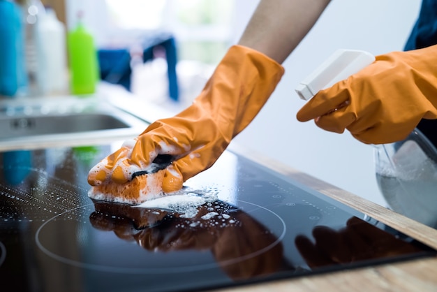 Housekeeping cleaning modern glass ceramic electric surface with a sponge in her kitchen housework