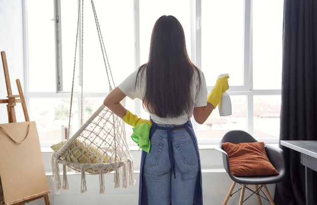 Housekeeping and cleaning service concept back view of a young woman cleaning lady in yellow