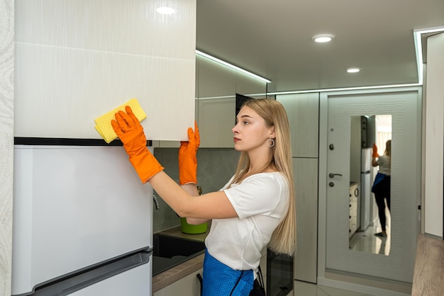 Housekeeping pretty young maid cleaning with spray and sponge in ktchen home work