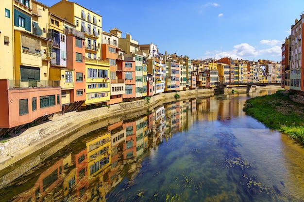 Houses of colorful colors on the banks of the river and reflection in the calm water on a sunny day Girona Catalonia