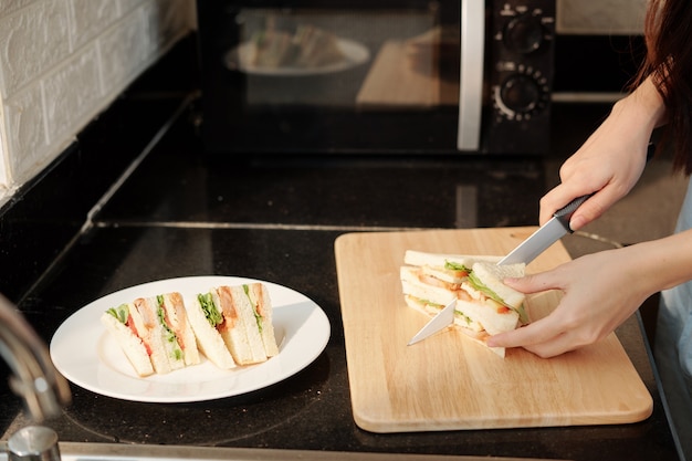 Housewife cutting chicken sandwich