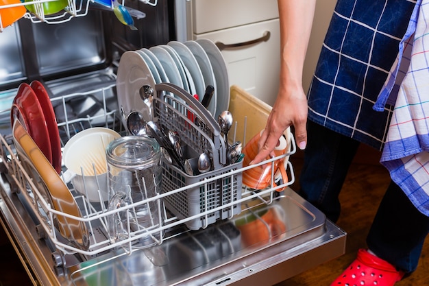 Housewife is doing the dishes with dishwasher