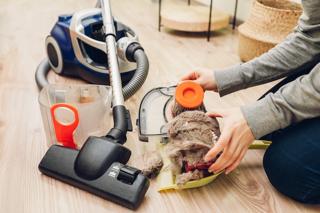 Housewife removes garbage and cats hair from dust filter of vacuum cleaner container at home