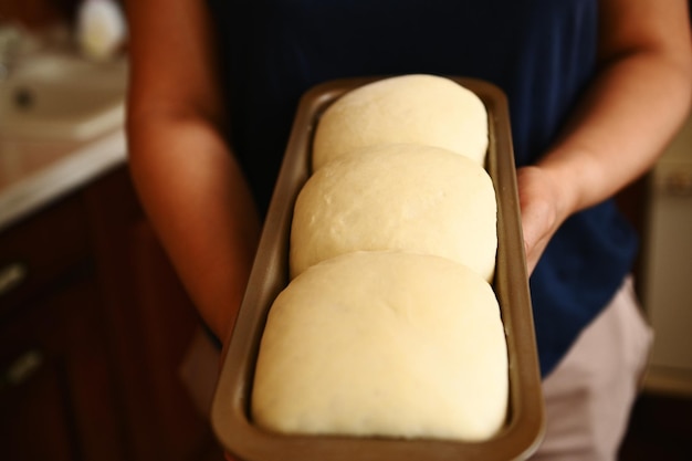 Housewife's hands holding a baking container with suitable yeast dough for bread Cooking healthy whole grain bread