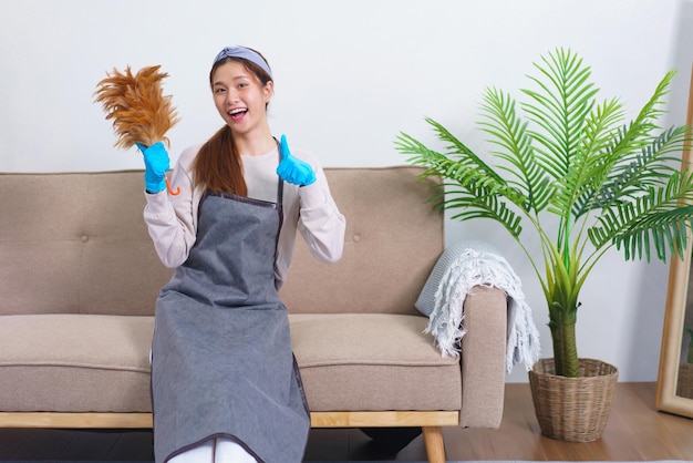 Housework concept Housemaid is holding feather duster and thumbs up gesture after cleaning house