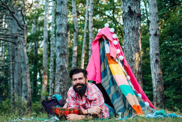 Photo hovel decorated party bearded man in hovel on sky background adventure travel shelter of branches