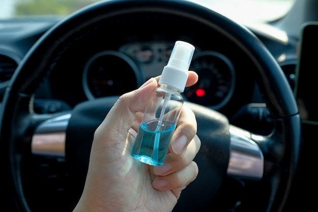 How to be safe from Coronavirus or COVID-19 ,The driver is sitting in the car and his hands are carrying a bottle of alcohol spray to clean and disinfect that may come from outside.