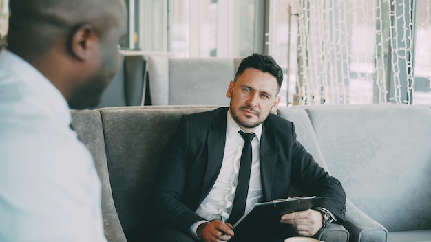 HR businessman having job interview with african american man and watching his resume application in modern cafe