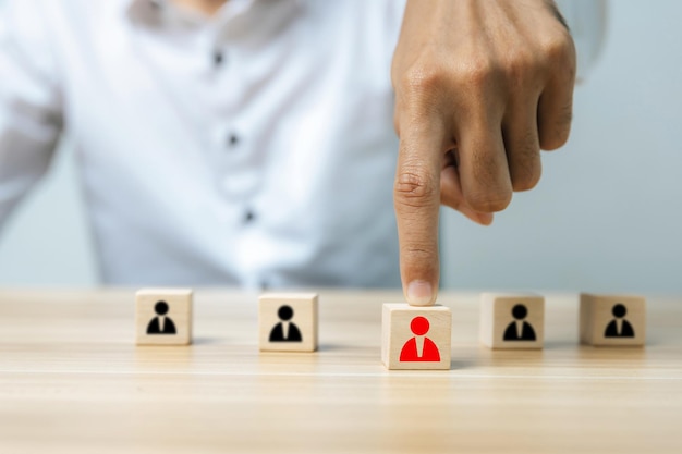 HR Management. business man hand choosing red human icon on wooden cube in front of black human icon, leadership, business management, team leader, business strategy, human resource management concept