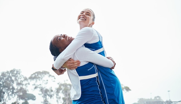 Hug celebration sports success or team support in netball training game or match with goals on court Teamwork fitness friends or excited young athlete girls with happy smile or winning together