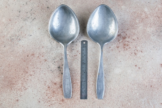 Huge aluminum spoons on concrete background. Copy space for text, food photography props.