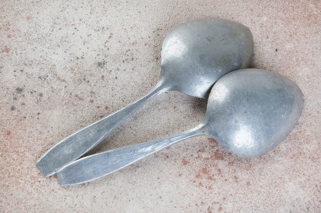 Huge aluminum spoons on concrete background. Copy space for text, food photography props.