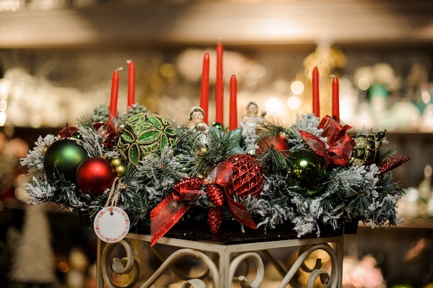 Huge christmas composition of snow covered fir-tree branches, candles, tapes, red and green toy balls and toy children