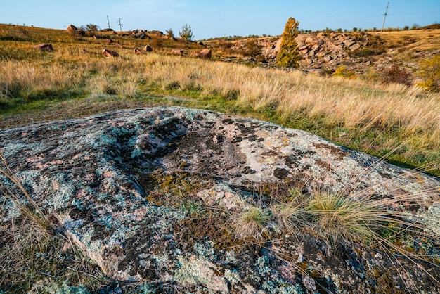 Huge deposits of old stone minerals covered with vegetation in a meadow filled with warm sun in picturesque Ukraine and its beautiful nature