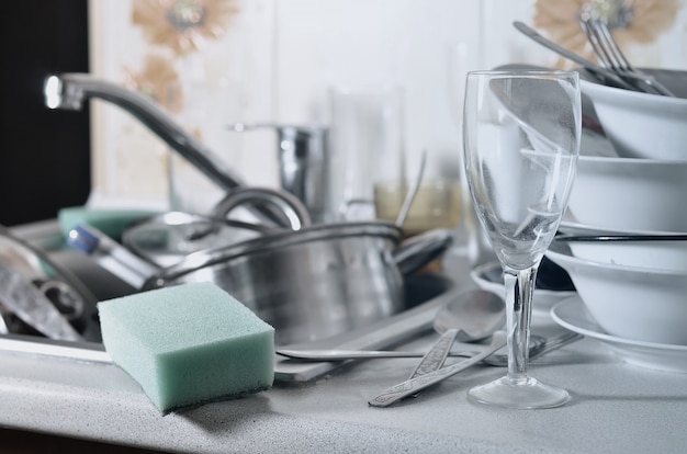 A huge pile of unwashed dishes in the kitchen sink and on the countertop