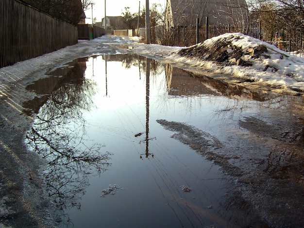 A huge puddle on the street during the spring flood There is still snow on the sides