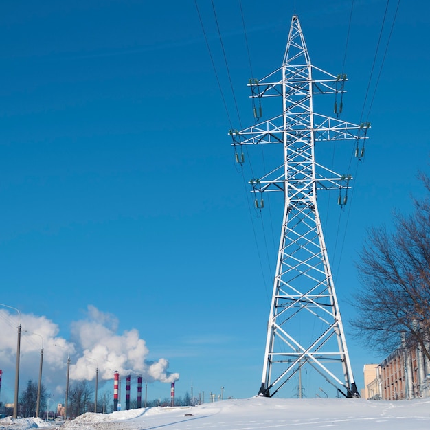 Huge pylon over clear blue sky with many chimneys on background