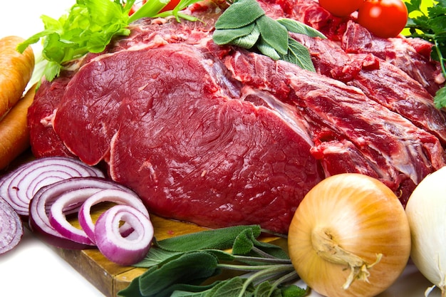 Huge red meat chunk with vegetables isolated over white background