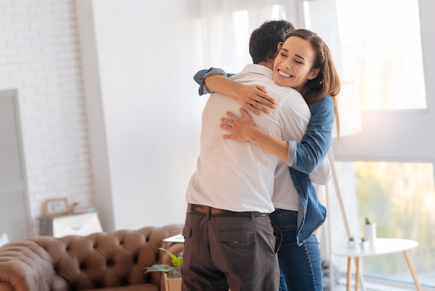 Hugging couple. Cheerful smiling woman hugging her beloved husband and feeling happy after getting a new interesting job in a famous company