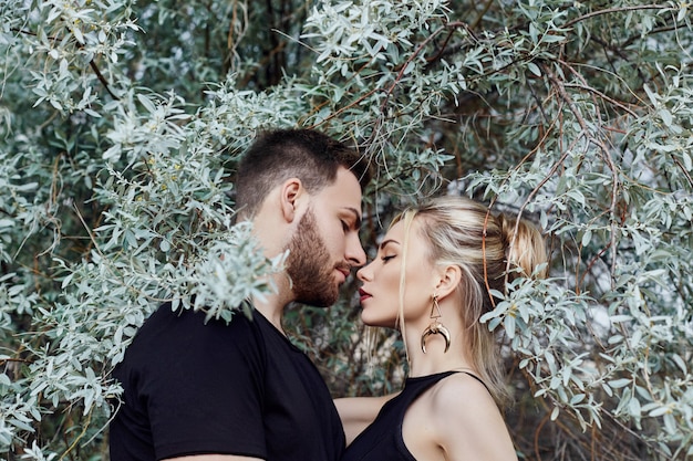 Hugs and kiss loving couple in branches of bushes