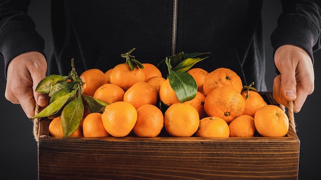 Human carrying a box with tangerines