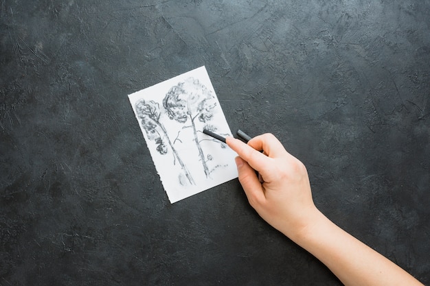 Photo human hand drawing with charcoal stick over black background