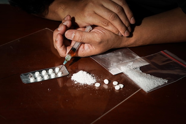 Photo human hand of a drug addict and narcotics syringe lying on the table against drug abuse