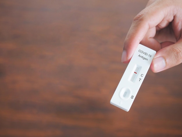 Human hand holding ATK or antigent test kit showing positive test