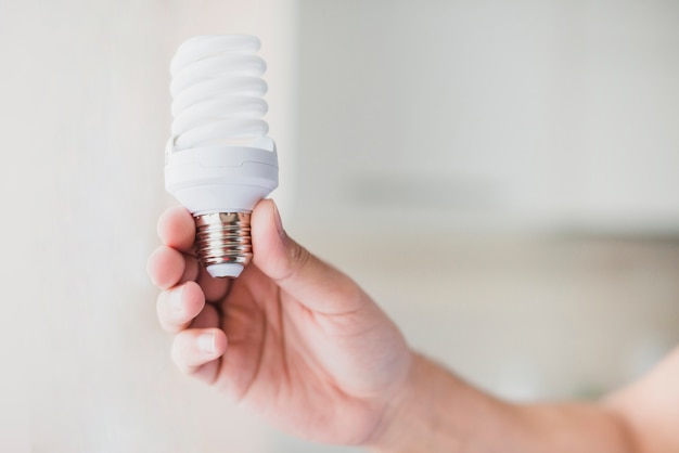 Human hand holding compact fluorescent light bulb