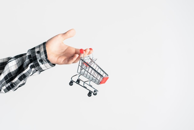 A human hand holding an empty shopping cart as the symbol of online shopping and ecommerce