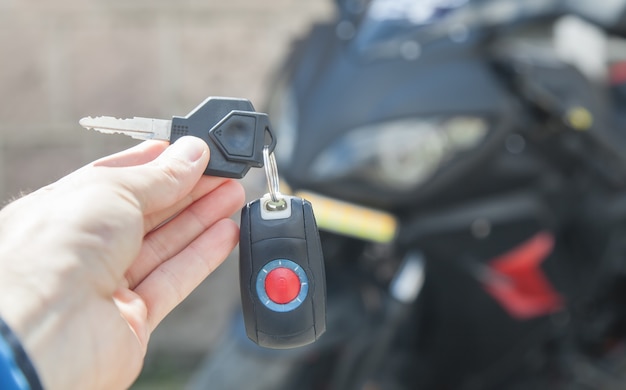 Human hand holding keys on the background of motorcycle Lifestyle