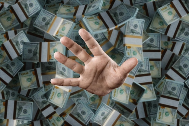 A human hand is sticking out of a pile of dollars Debts credit mortgage jackpot winnings Man drowned in money